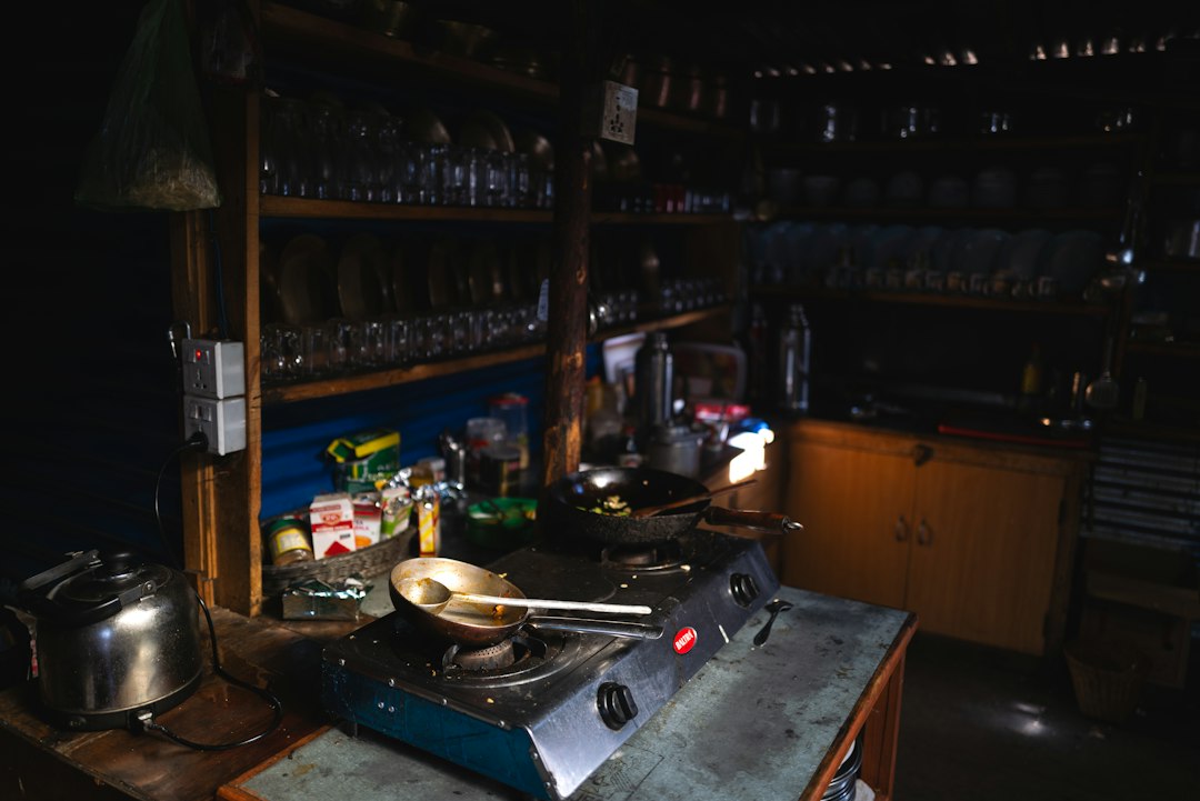 A dimly lit kitchen counter with a stovetop and utensils